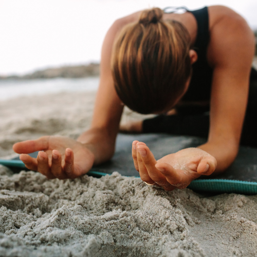 A woman spending time in solitude on a beach to connect with herself.