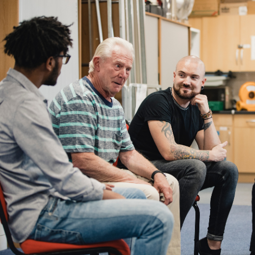 A diverse group of individuals engaged in conversation while seated in chairs.
