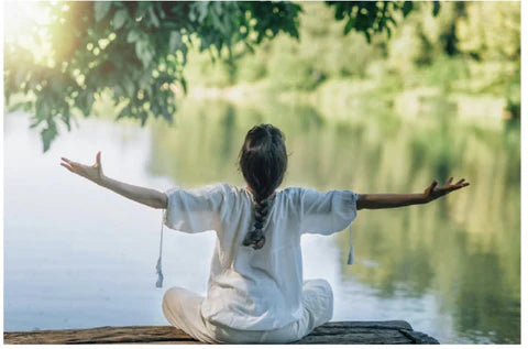 Woman practicing yoga on a serene waterfront, surrounded by calm waters and a peaceful atmosphere.