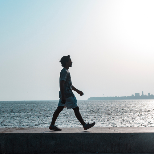 An image of a man walking along the water.
