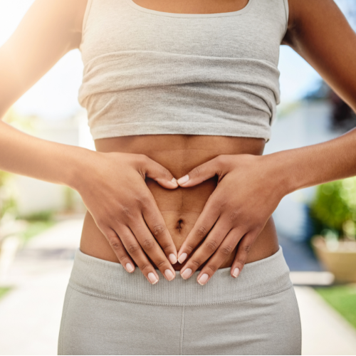 Image of a woman with her hands over her stomach in the shape of a heart.