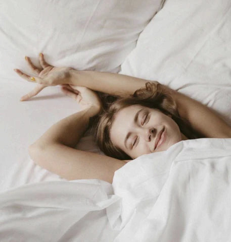 Smiling woman in bed, looking well-rested after a good night's sleep.
